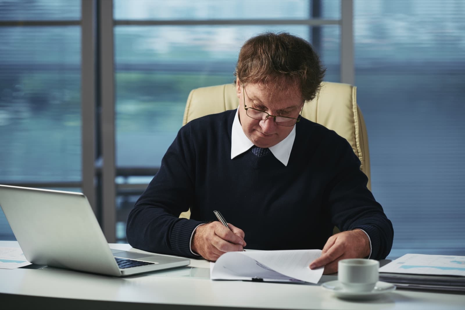 A manager reviewing printed financial paperwork at an office desk
