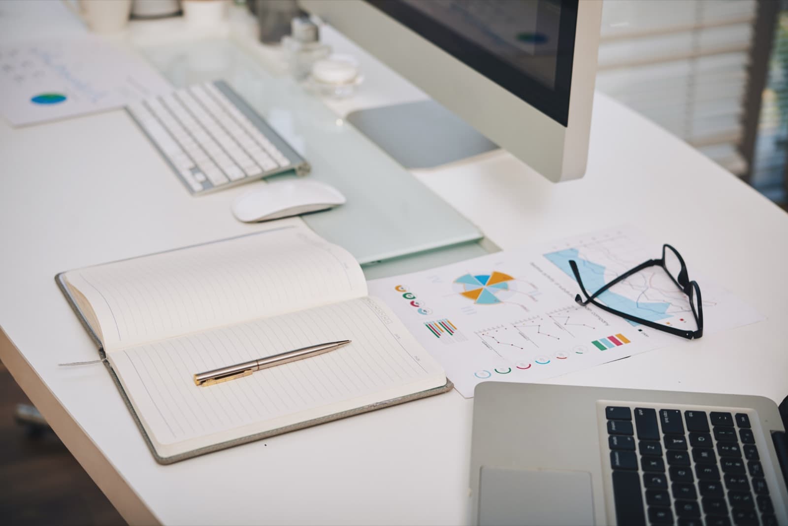 A finance workspace with printed analysis charts, a notebook and a computer